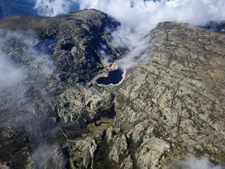Aerial drone view of lakes in Serra da Estrela, Portugal with clouds above and fog passing. Travel and adventure. Nomad life. Hiking lifestyle. Observatory. Best destinations in the world. 
