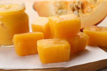 Frozen pumpkin puree cubes with ingredient on wooden board, closeup