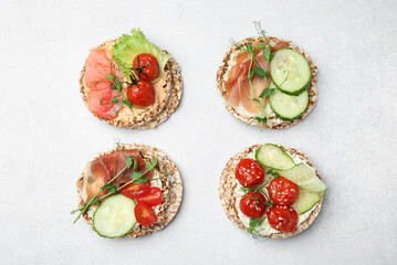 Set of crunchy buckwheat cakes with different ingredients on white background, flat lay