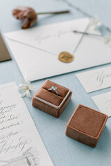 Engagement ring with a diamond in a box on a light blue background. Invitations on handmade paper...
