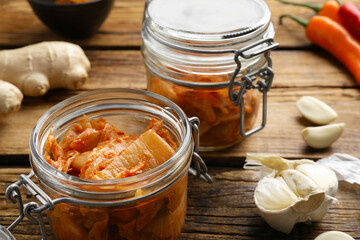 Delicious kimchi with Chinese cabbage and ingredients on wooden table, closeup
