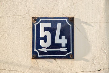 Weathered grunge square metal enameled plate of number of street address with number 54