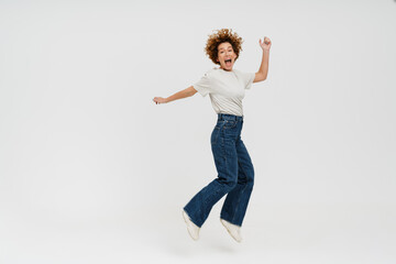 Ginger curly woman wearing t-shirt laughing and jumping