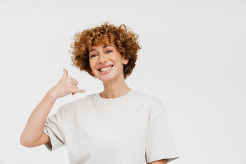 Ginger curly woman smiling and showing handset gesture
