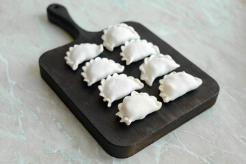 Beautiful raw stuffed dumplings on a wooden cutting board
