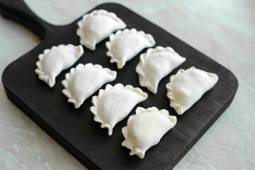 Beautiful raw stuffed dumplings on a wooden cutting board