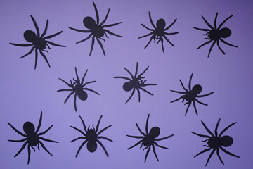 Black spiders on a purple background, color background and silhouettes of spiders, festive scary background, frightening decoration for Halloween, paper crafts gifts, material for needlework