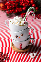 Tower of cups in form of snowman on red background. Hot beverage  with marshmallow. Traditional winter holiday drink.