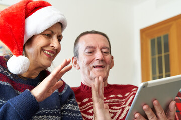Senior woman with santa hat and male waving during Christmas video call