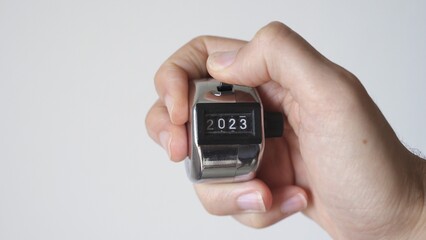 Countdown to 2023 concept. Hand with metal tally counter going from 2022 to 2023