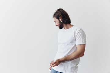 Stylish man in a white t-shirt with wireless headphones in his ears having fun listening to music...