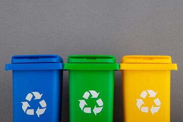 Plastic yellow, green and blue trash can on a gray background