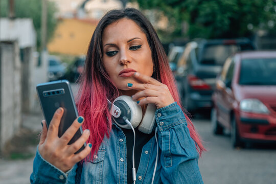 woman with mobile phone in the street and expression of doubt or decision