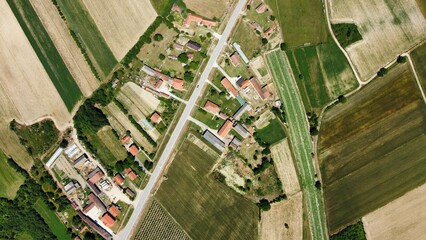 Arial shot of a huge green farm with plowed land and a small village in the middle of it