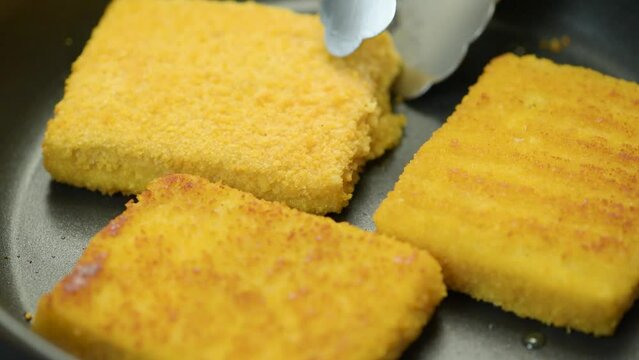 Fish sticks. The process of cooking fish sticks in a pan, close-up. Breaded fish fillet.