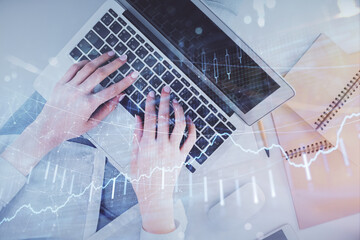 Double exposure of woman hands working on computer and forex graph hologram drawing. Top View. Financial analysis concept.