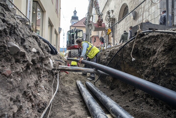 Workers install underground pipes for water, sewerage, electricity and fiber optics for the...