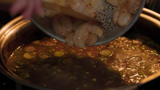 chef dropping in the shrimp into the Louisiana gumbo soup