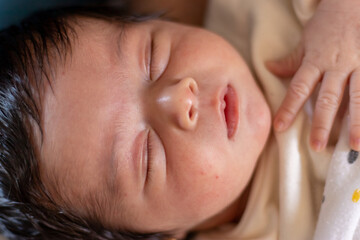 close up shot of a cute newborn baby with heavy black hair