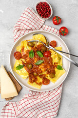 Pasta ravioli with tomato sauce and olives with basil and cheese on a gray background