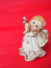 Guardian angel plays the flute. Figurine of a red-haired girl in a white dress with wings and a...