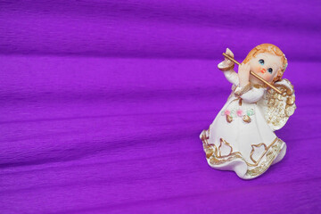 Guardian angel plays the flute. Figurine of a red-haired girl in a white dress with wings and a...