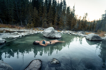 Woman floats in and enjoys the thermal healing waters geothermal hot springs in nature in the back country of Idaho USA.