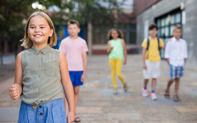 Obraz premium Closeup portrait joyful preteen girl walking along city street on sunny summer day..
