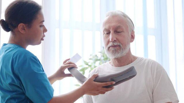 Woman doctor removing cervical collar from her senior patient, healing, health