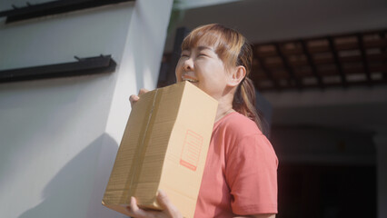 Asian woman rejoices in receiving a parcel in front of her house.