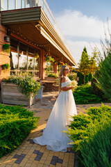 Fototapeta premium beautiful blonde bride with a bouquet of callas on the path in the garden.