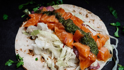 Healthy breakfast concept. Salmon, lettuce, herbs and pesto sauce on a tortilla. Tasty food in restaurant. Close-up.