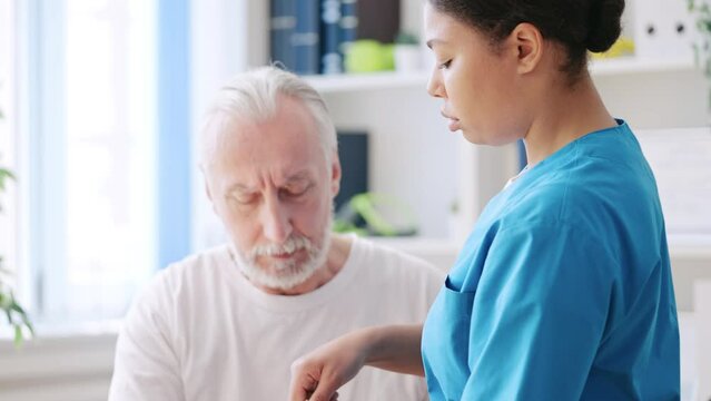 Female orthopedist fixing cast to senior patient's injured hand in a hospital