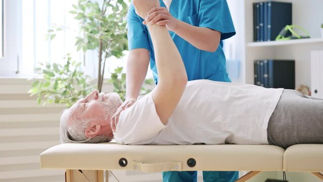 Rehabilitation doctor helping senior patient do arm exercise, injury treatment