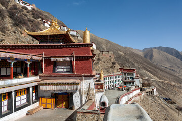 DRIGUNG MONASTERY, TIBET: general view of colorful buildings and dry sunny winter landscape. Drigung Monastery is a notable monastery in the Lhasa Prefecture, Tibet, known for performing sky burials