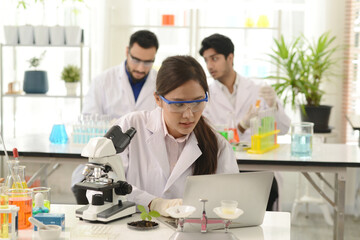 A group of research medical scientists, male and female, working with microscope testing equipment in the laboratory. A professional scientist analyzing biochemical samples on a microscope in a lab.