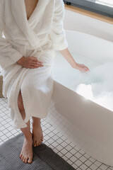 Woman waiting until hot water fill the bathtub