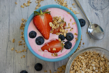 Strawberries, dry oatmeal, yogurt on a wooden background