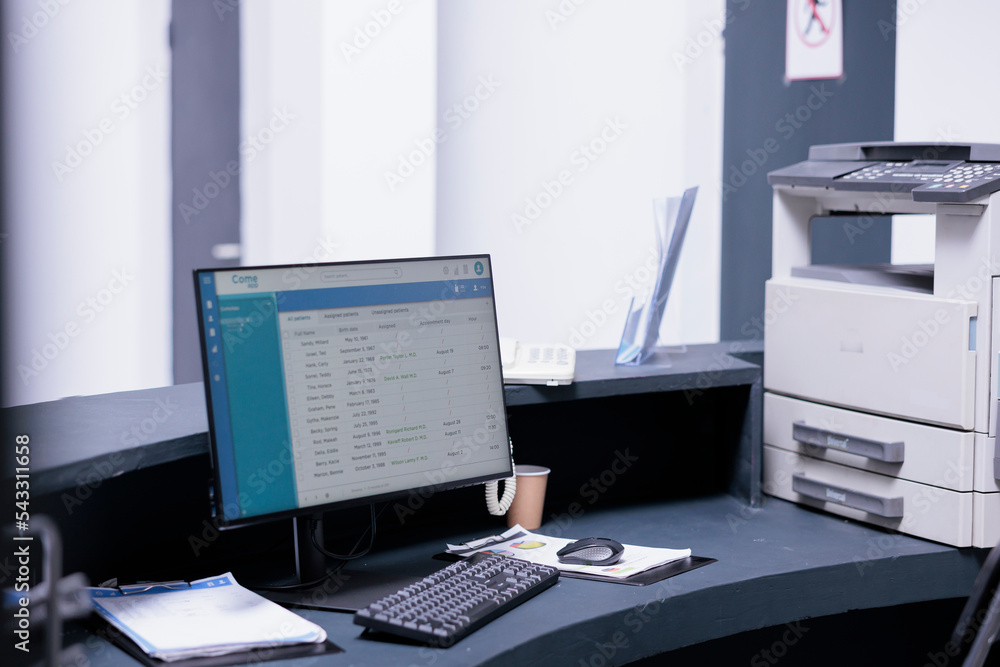 Poster list of patients displayed on desktop computer screen on reception counter of medical clinic. no one