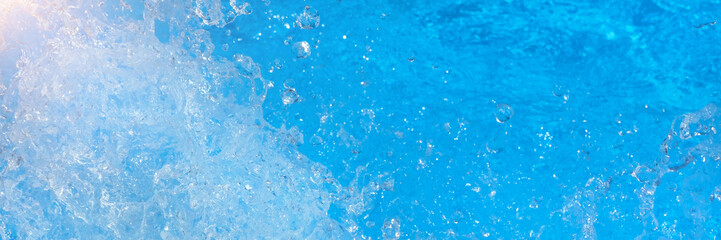 Surface of blue swimming pool water with light reflection, splashes and waves. Texture of transparent blue water with waves in swimming pool. Trendy abstract nature background. long banner.