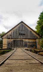 Fototapeta na wymiar Old wooden barn with a set of train tracks on a bridge leading to it. 