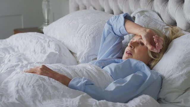 Menopausal mature woman suffering with insomnia awake in bed at home - shot in slow motion