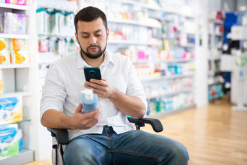 Disabled man in wheel-chair photographing medicine with smartphone in drugstore.