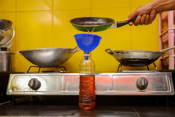 household waste management.  pouring used cooking oil from the frying pan into bottles for...