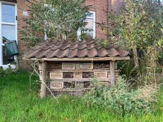 Bee hotel near a house on the street. Bee hotel or bee house is an analogue of a birdhouse for...