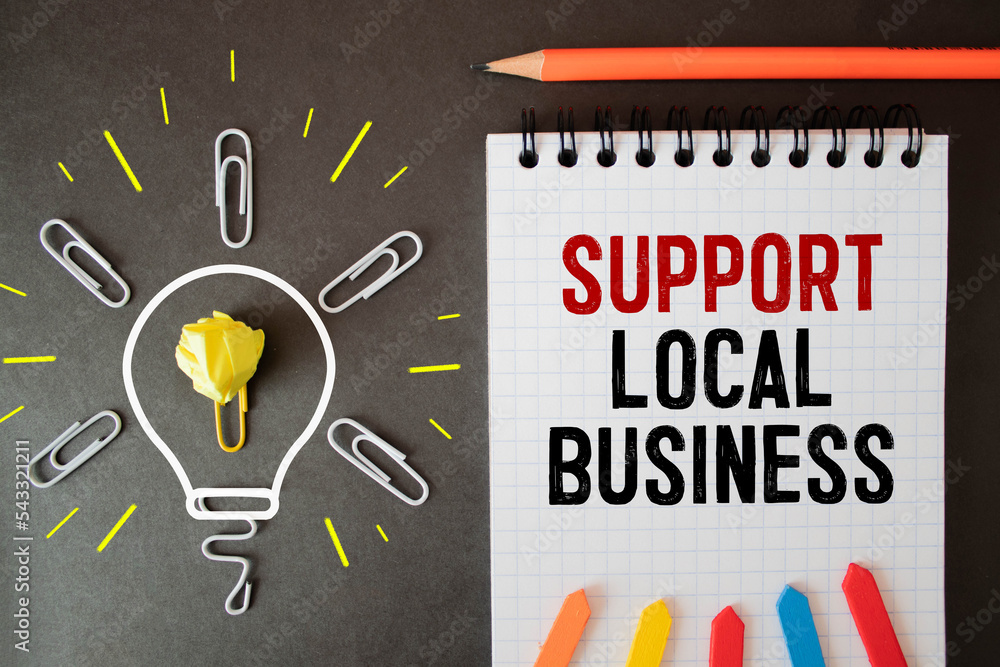 Poster support local business text written on a notepad on a table with a cup of coffee, glasses and a pen,