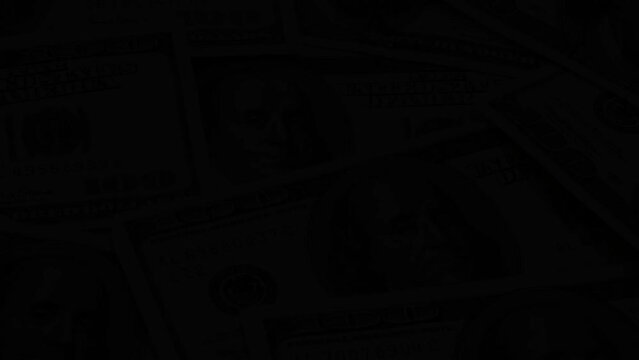 Image Of Several One-hundred Dollar Bills Spread Out Fading To Black Background
