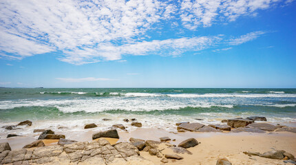 Looking out to the horizon of the Pacific Ocean from Alexandra Headland, Maroochydore. The sky is blue with inspiring white clouds, the ocean water is green with white breaking surf and the shoreline 