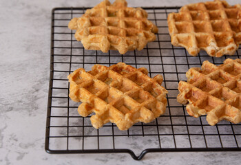 Homemade Belgian waffles on a grill on a gray texture background. Side view