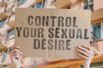 The phrase " Control your sexual desire " is on a banner in men's hands with blurred background. Plan. Pointing. Romance. Safe. Safety. Security. Seductive. Intimacy. Male. Pleasure. Adult. Lover